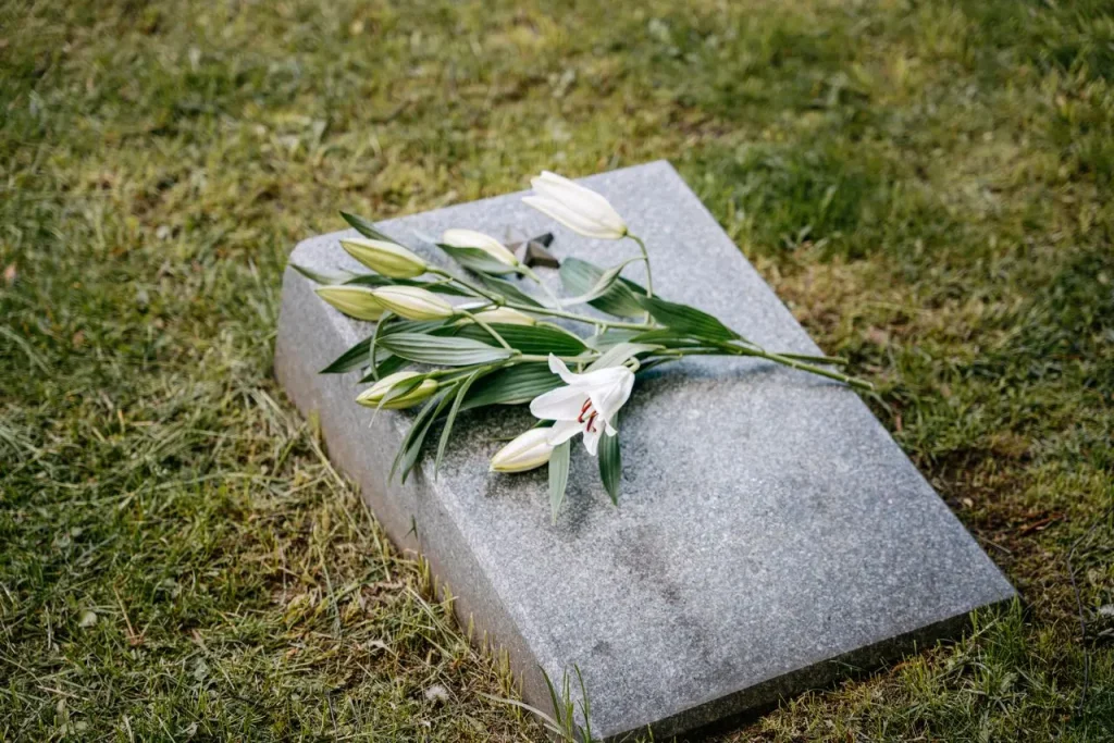 Flores brancas sobre lápide de granito em um cemitério.