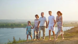 Família de cinco pessoas caminhando de mãos dadas ao ar livre.