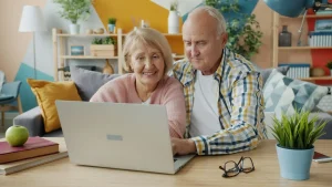 Casal idoso usando notebook em casa.