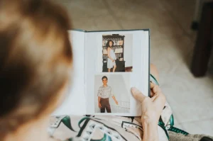Pessoa observa um álbum de fotografias antigas com retratos de familiares.