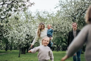 Família com crianças passeando em um parque arborizado.